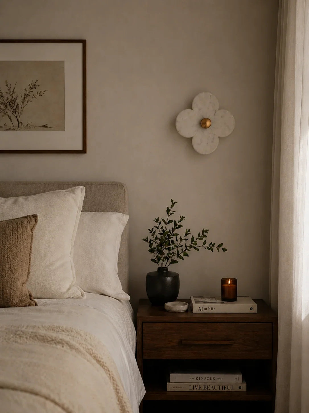 The Petalo hand-carved alabaster clover wall sconce with brushed brass finish, styled on a bedroom wall