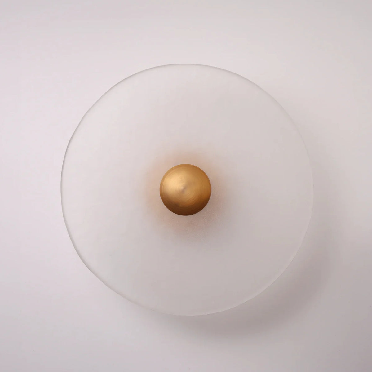 The Orbis frosted glass disc wall sconce in a matte brass finish