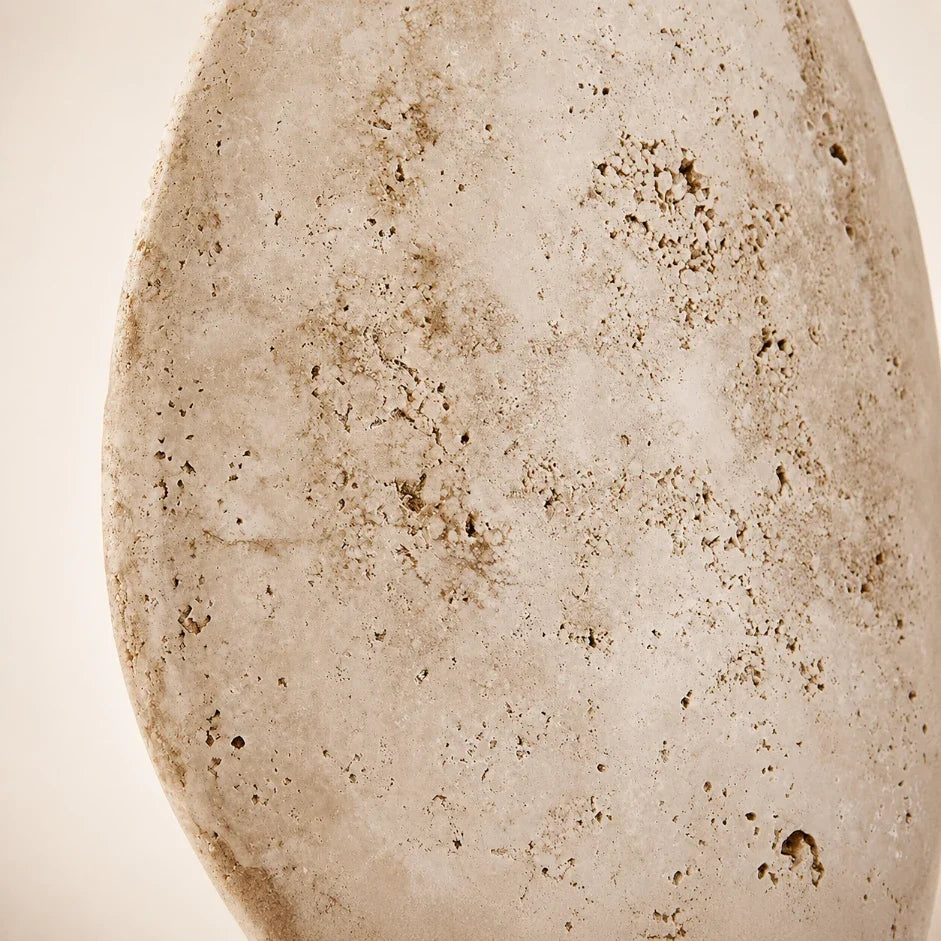 The Luma natural travertine stone wall light lit, washing warm light up and down the wall
