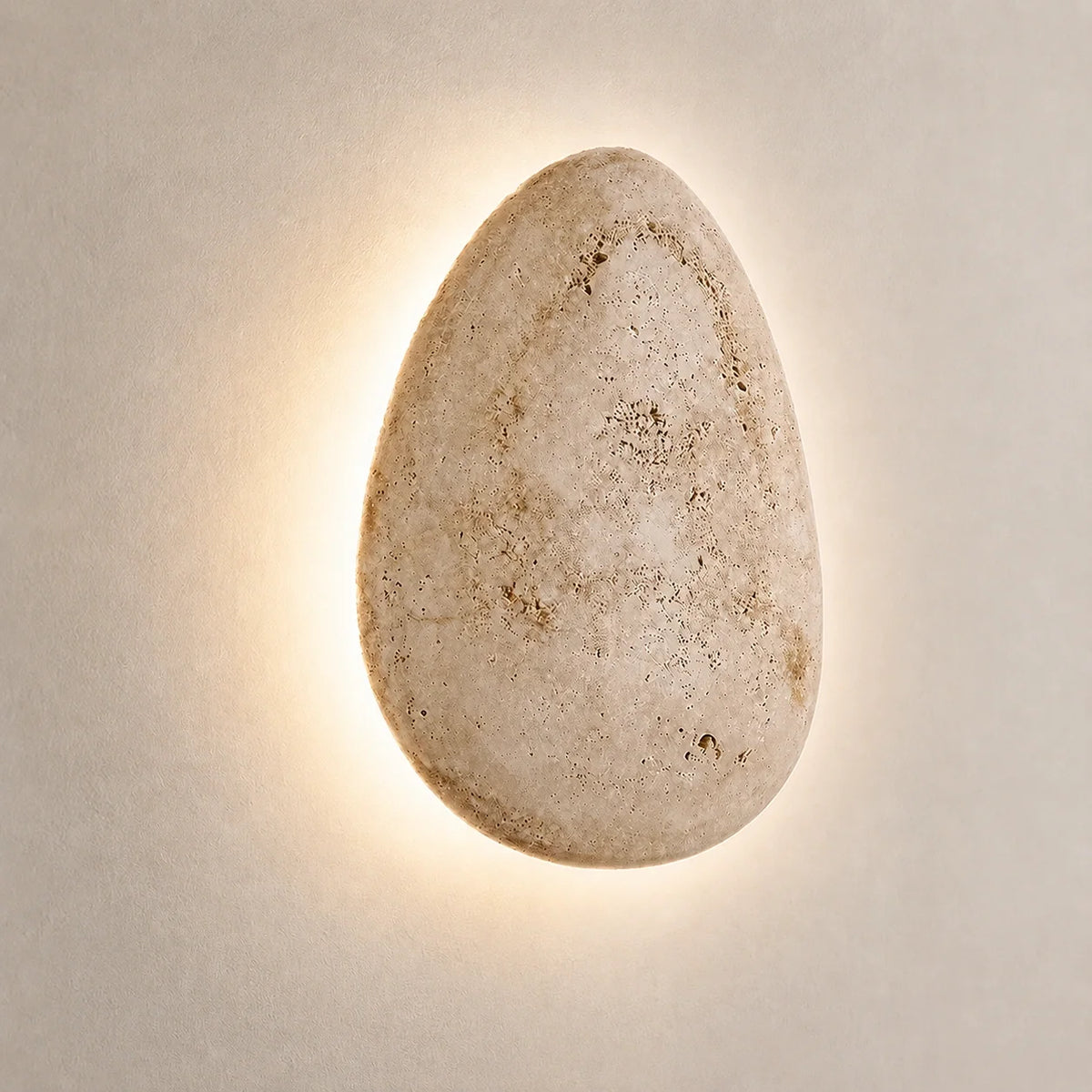 The Luma travertine wall light casting an up and down glow across a wall