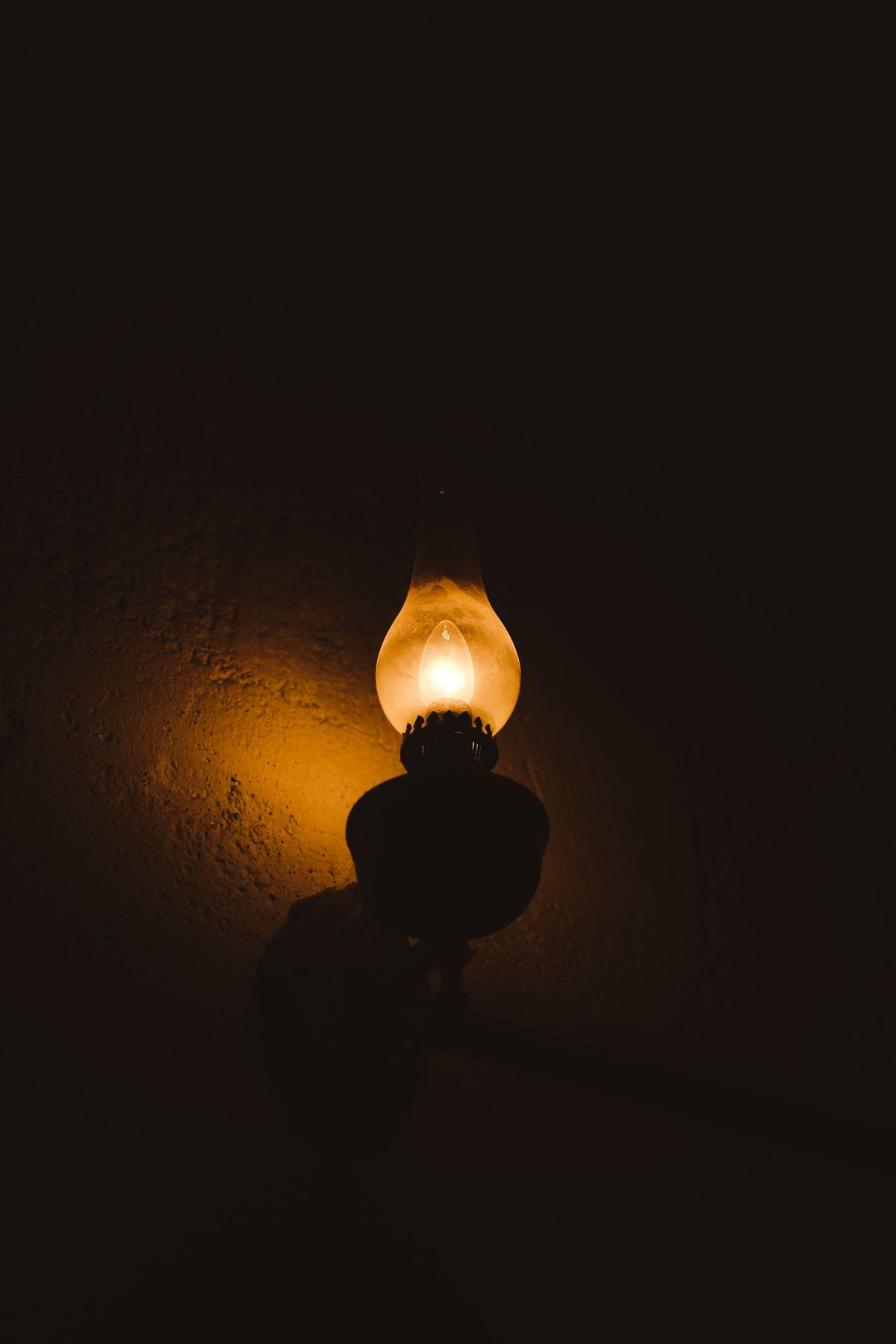 Illuminated wall lamp glowing warm against dark wall - choosing a wall light