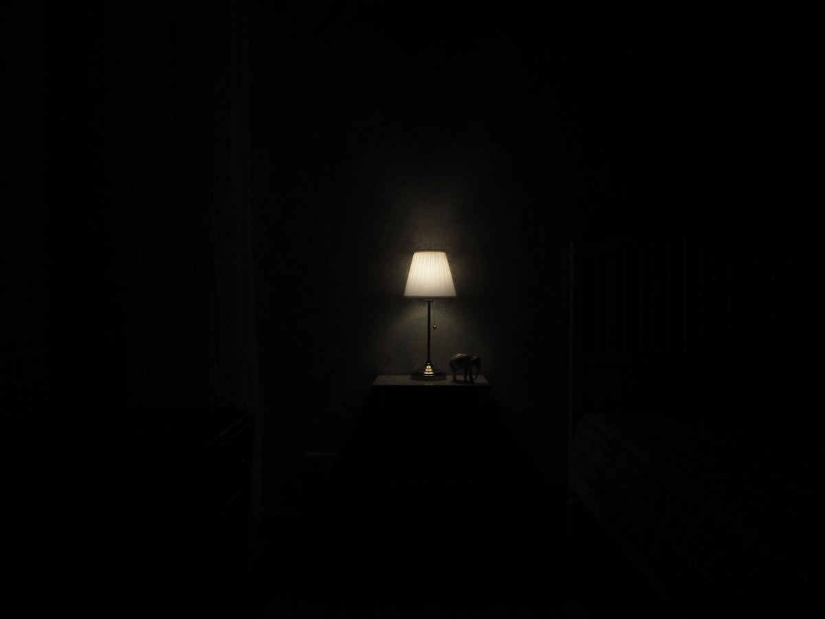 Cordless-style lamp glowing on a nightstand in a dark room