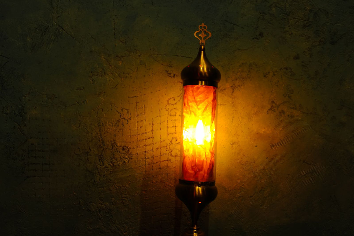Brass lamp with golden shade glowing warm on a wall