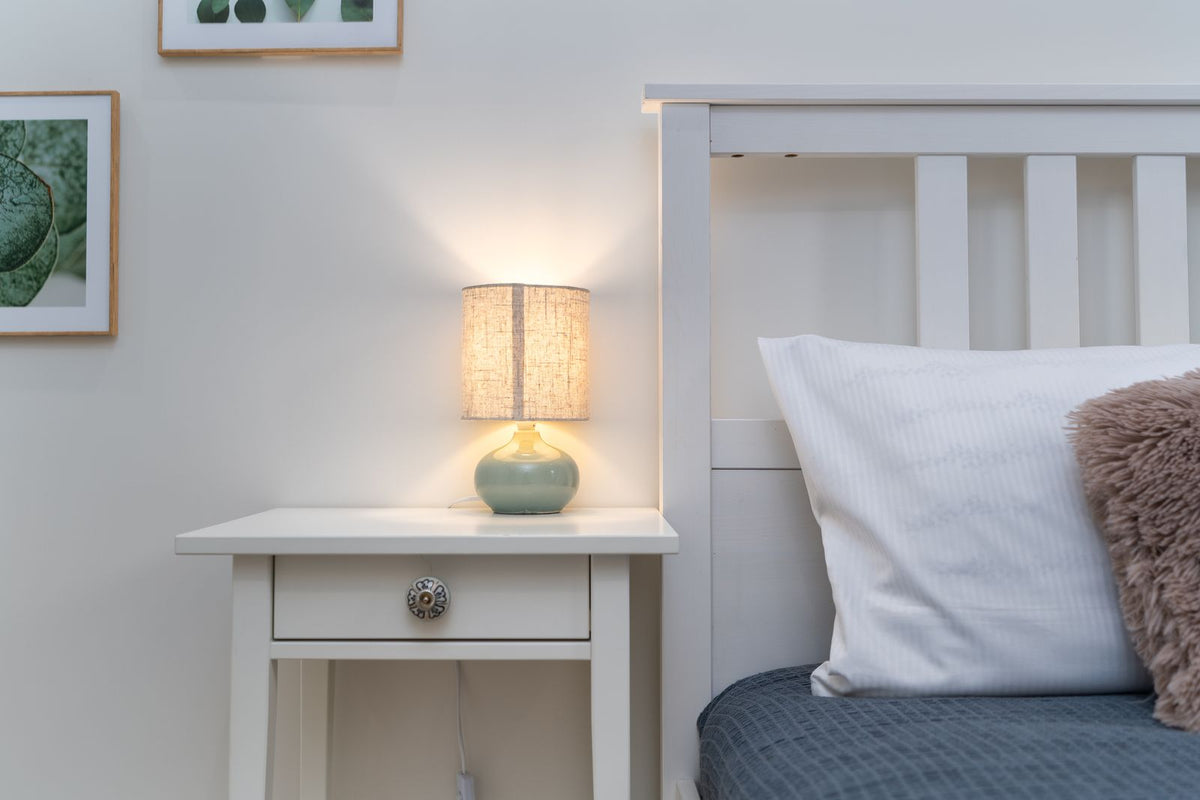 Cozy bedroom with lit lamp on nightstand beside bed