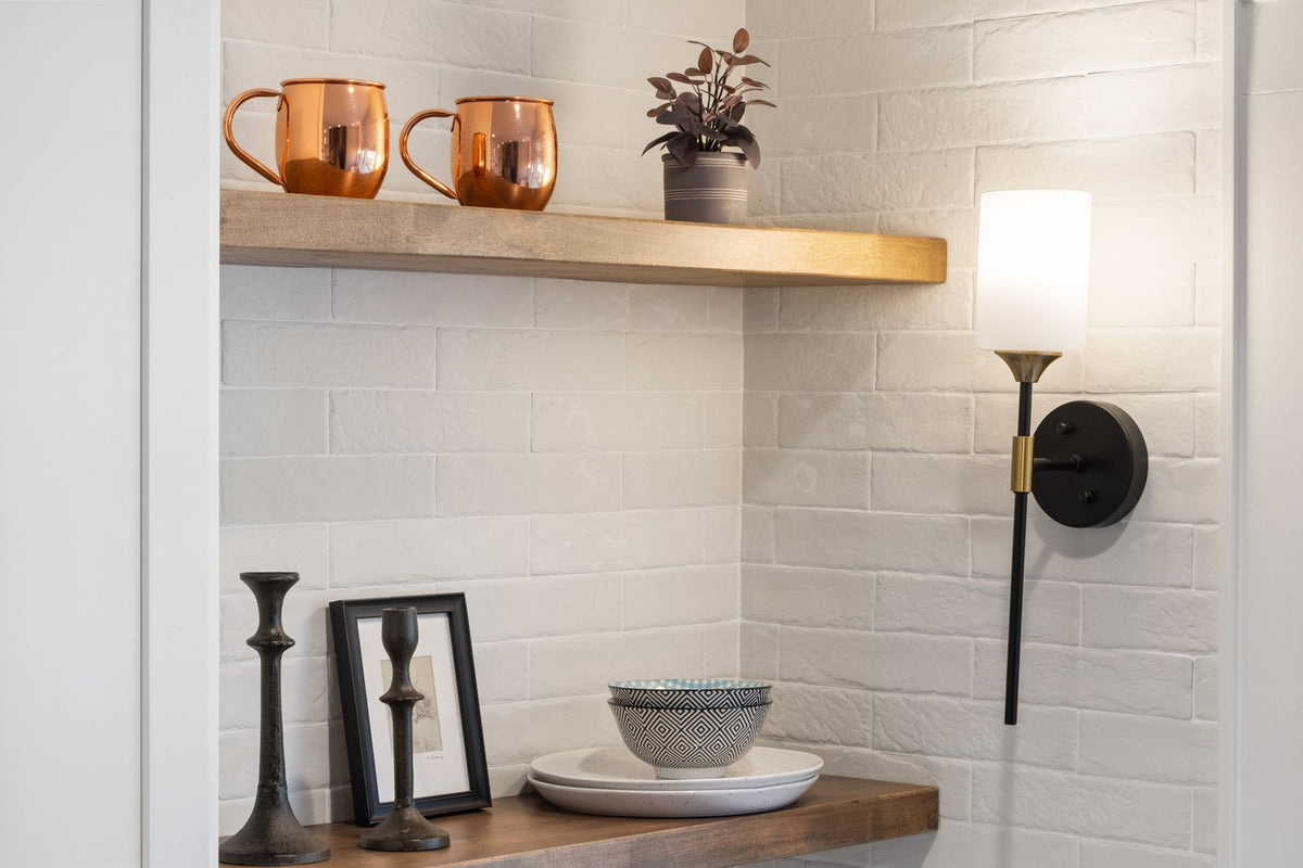 Wall sconce beside open timber kitchen shelving with copper mugs