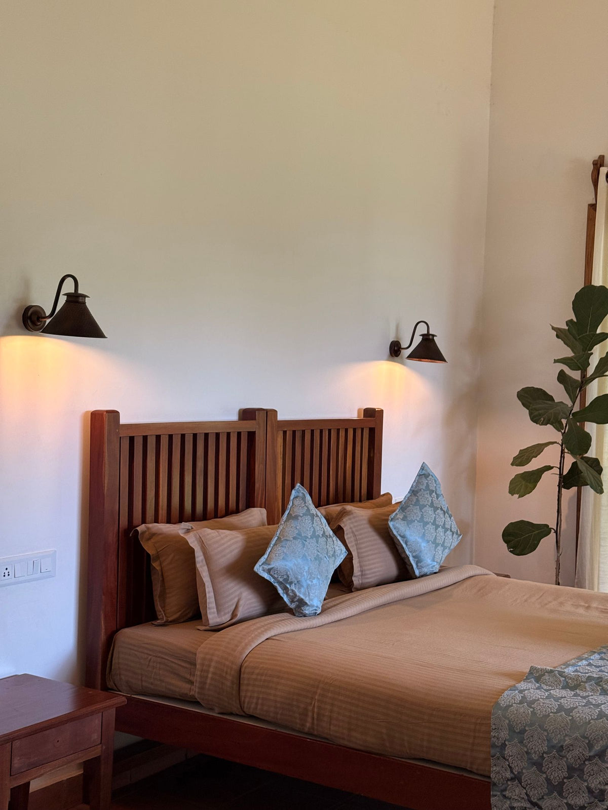 Pair of black swing-arm wall lamps either side of a timber bedhead