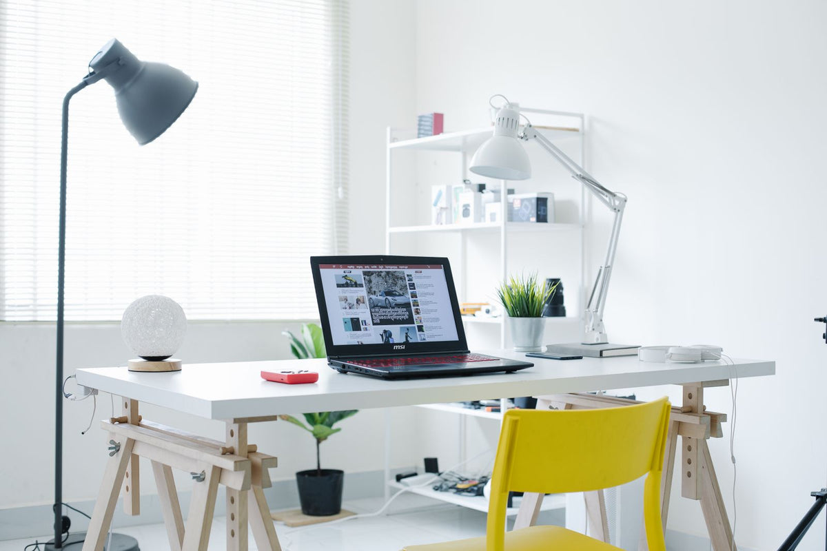 Bright white home office with a desk, task lamp and shelving