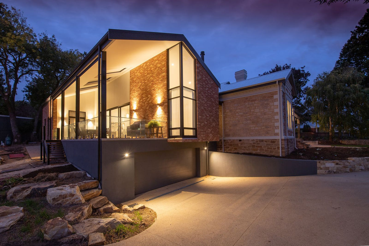 Modern house facade with glowing outdoor wall lights at dusk