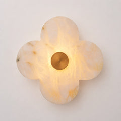The Petalo alabaster clover sconce lit, glowing warm amber