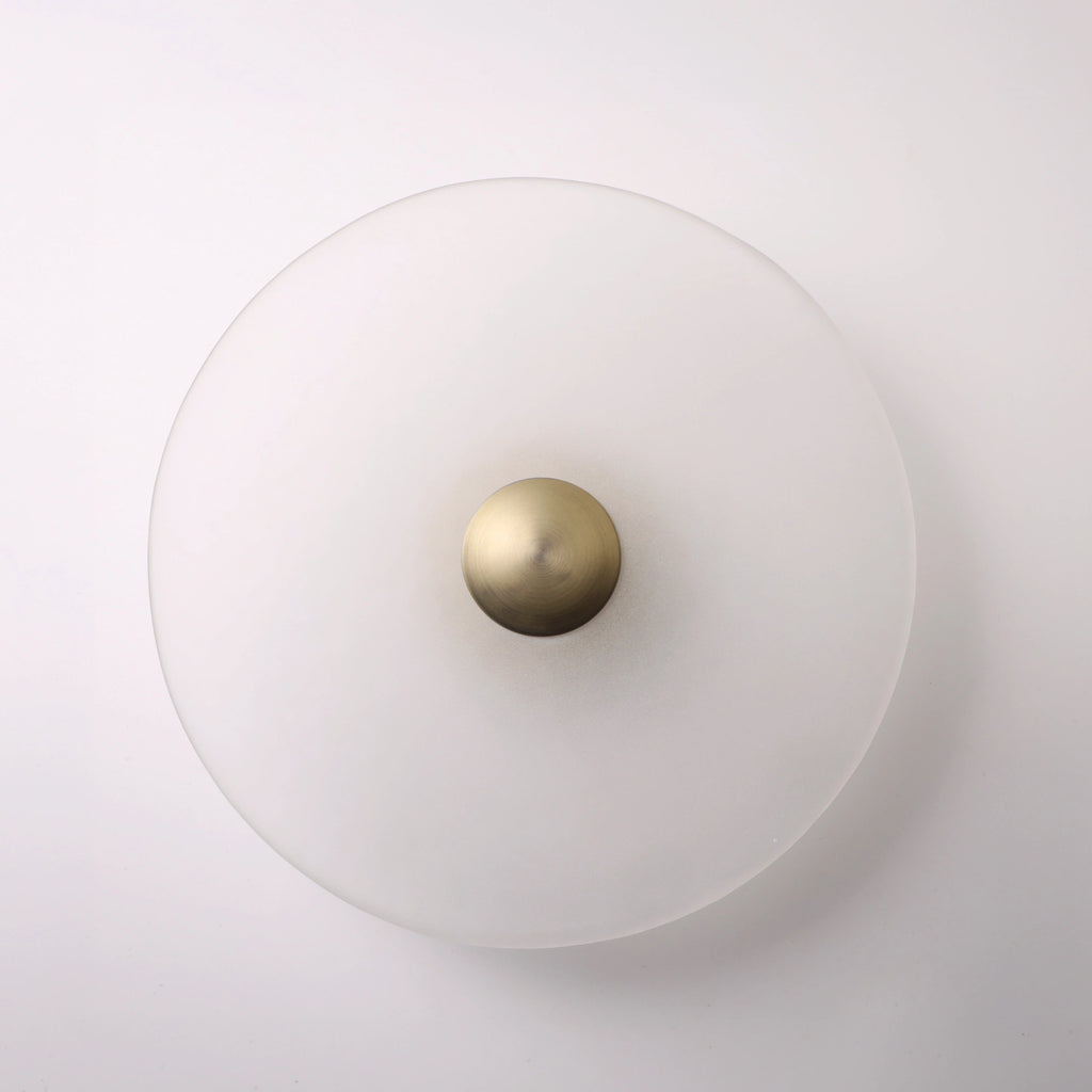 The Orbis wall sconce in bronze, lit with warm LED halo