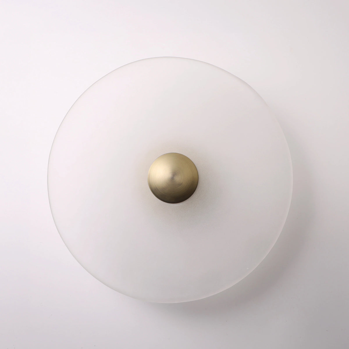 The Orbis wall sconce in bronze, lit with warm LED halo