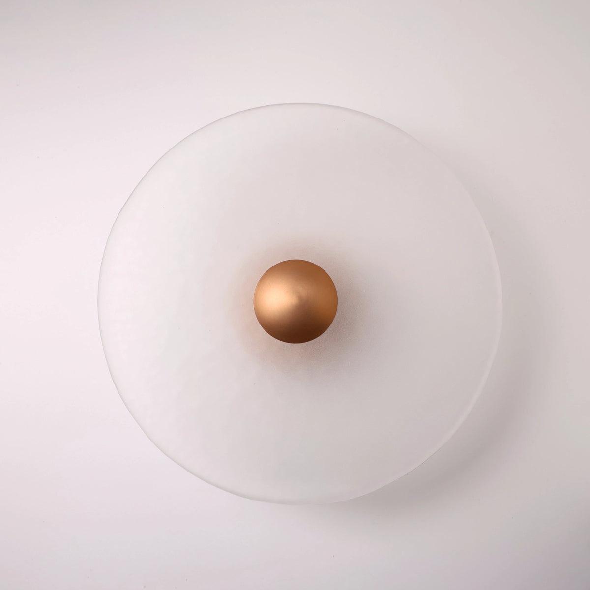 The Orbis wall sconce in copper, lit with warm LED halo