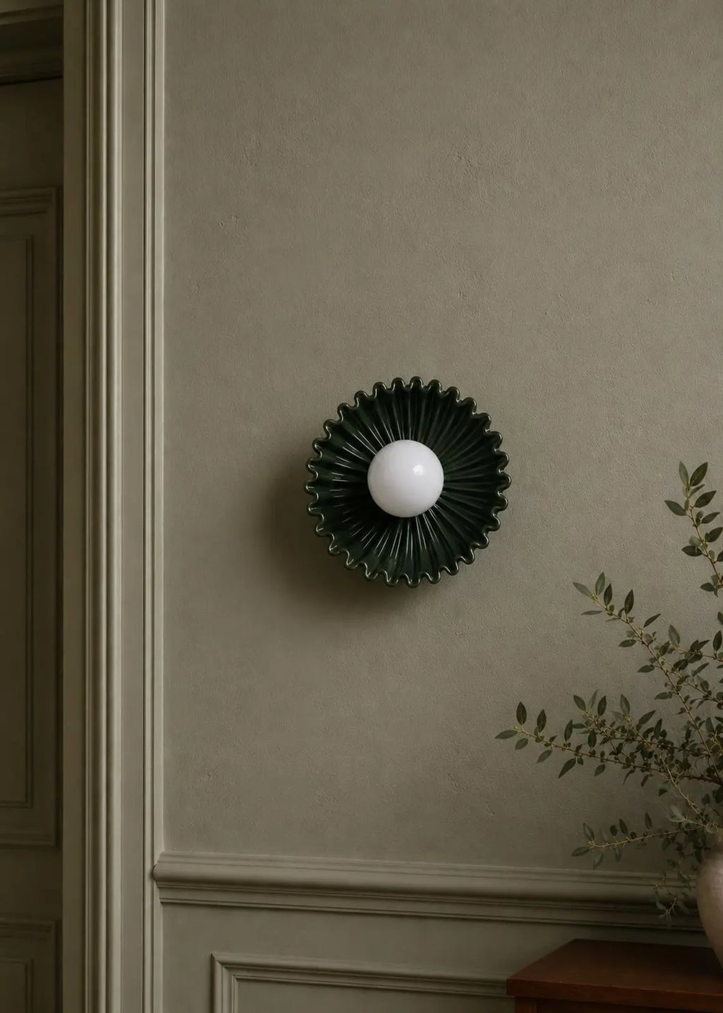 The Solara dark green ceramic sunburst sconce styled on wall
