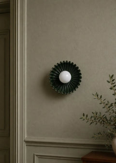 The Solara dark green ceramic sunburst sconce styled on wall