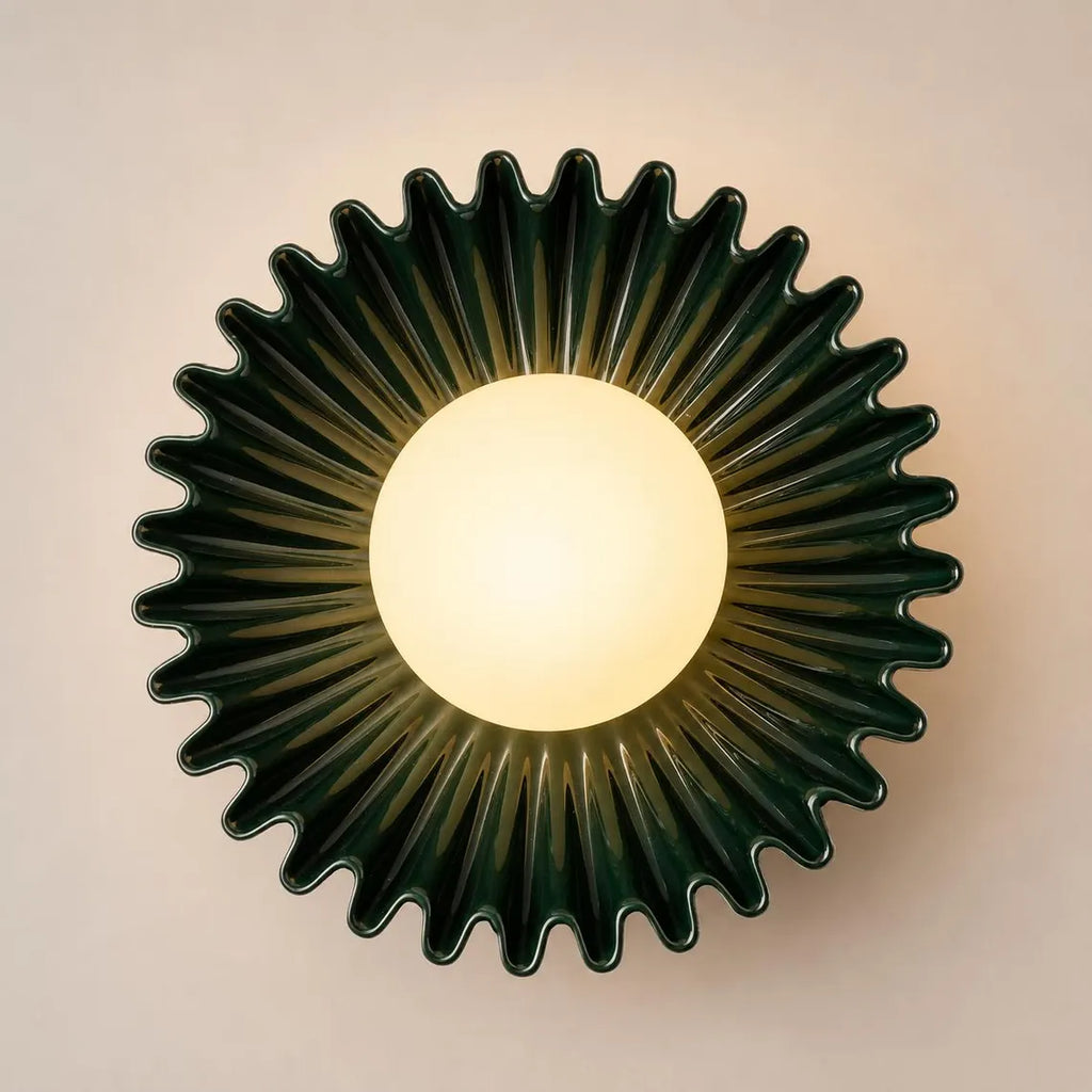 The Solara dark green ceramic wall sconce lit