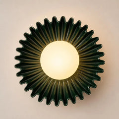 The Solara dark green ceramic wall sconce lit