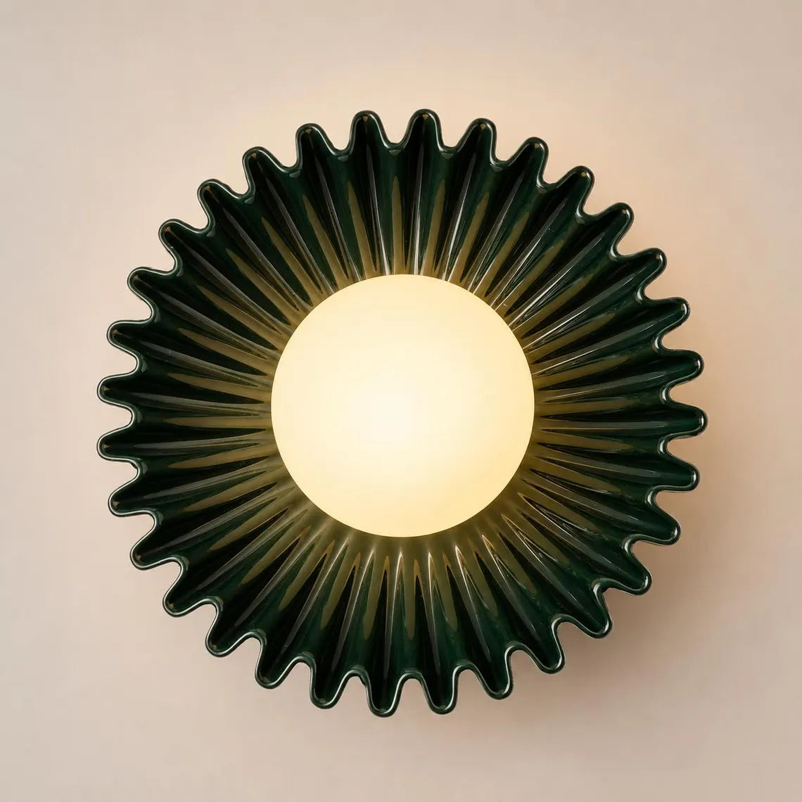 The Solara dark green ceramic wall sconce lit
