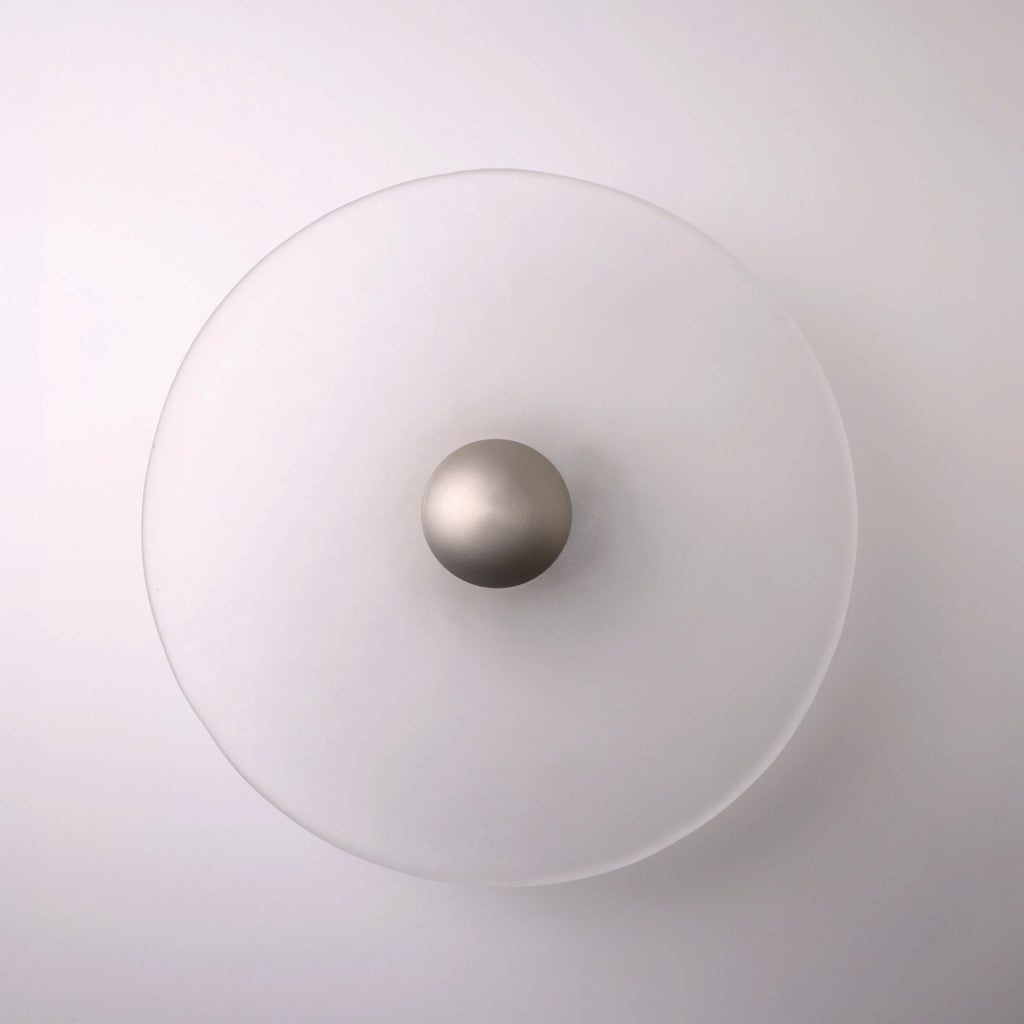 The Orbis wall sconce in nickel, lit with warm LED halo