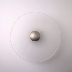 The Orbis wall sconce in nickel, lit with warm LED halo