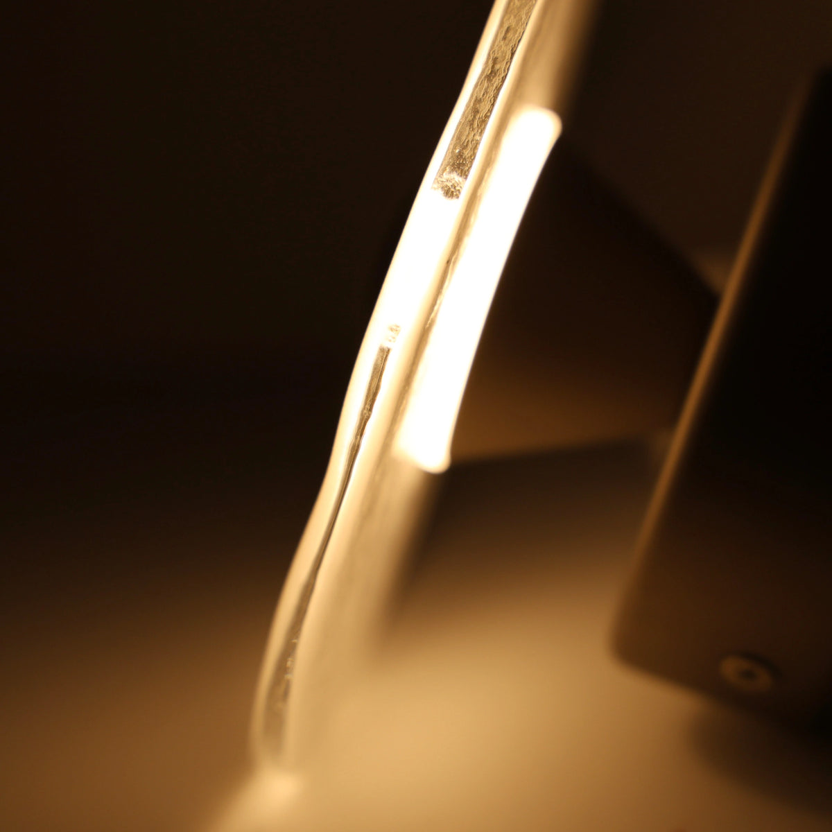 The Orbis nickel wall sconce, warm halo glow in a dark room