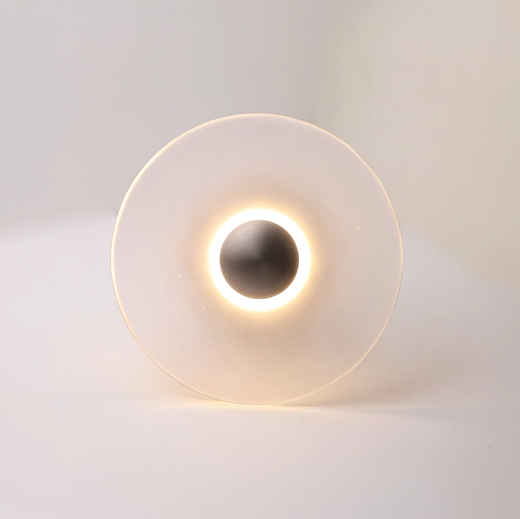 The Orbis nickel wall sconce glowing warm white