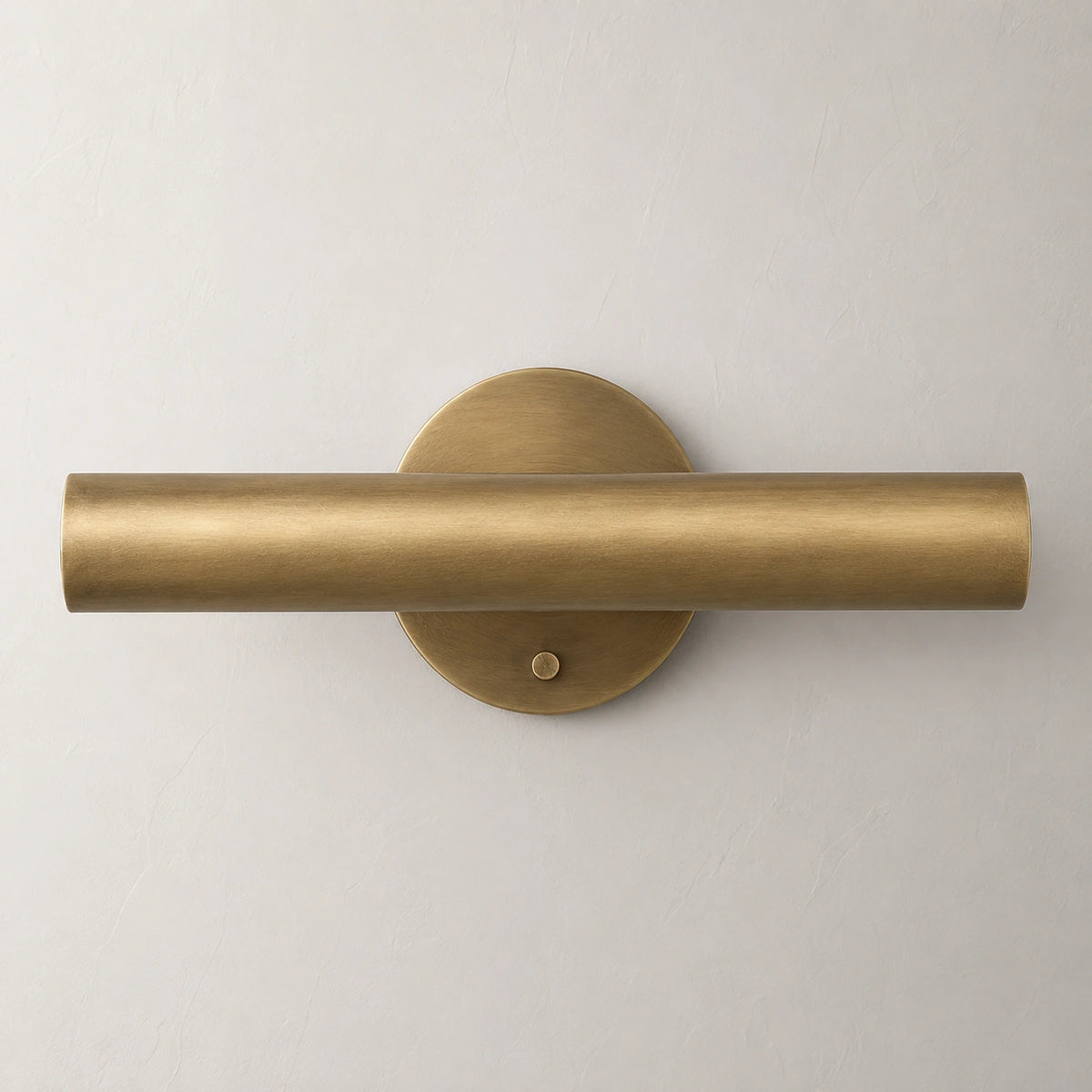 The Aurum brass wall sconce lit with warm white glow