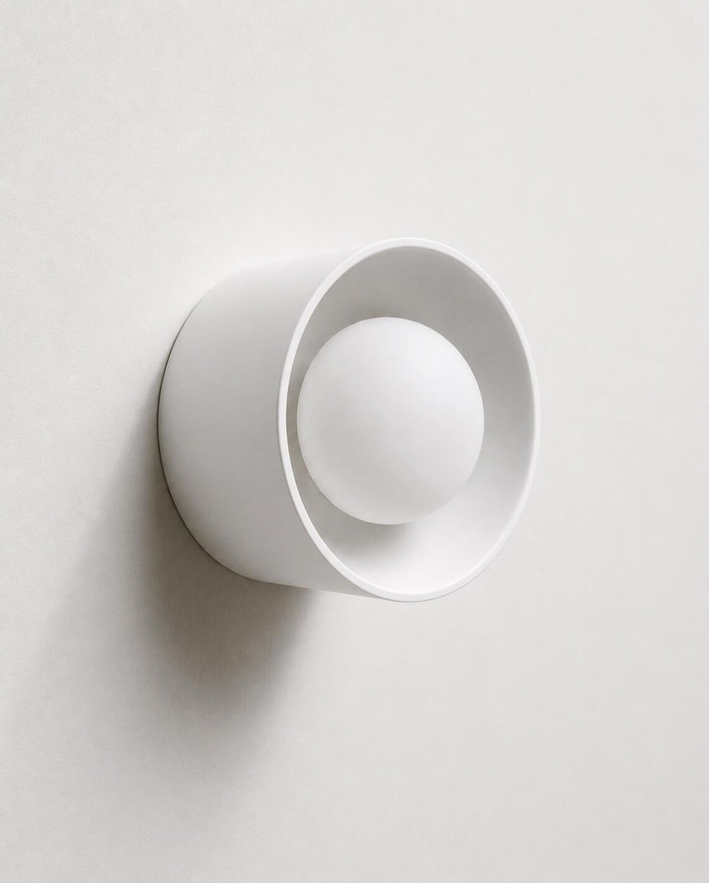 The Volta ceramic wall sconce lit with warm glow