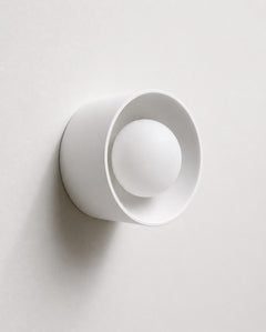 The Volta ceramic wall sconce lit with warm glow