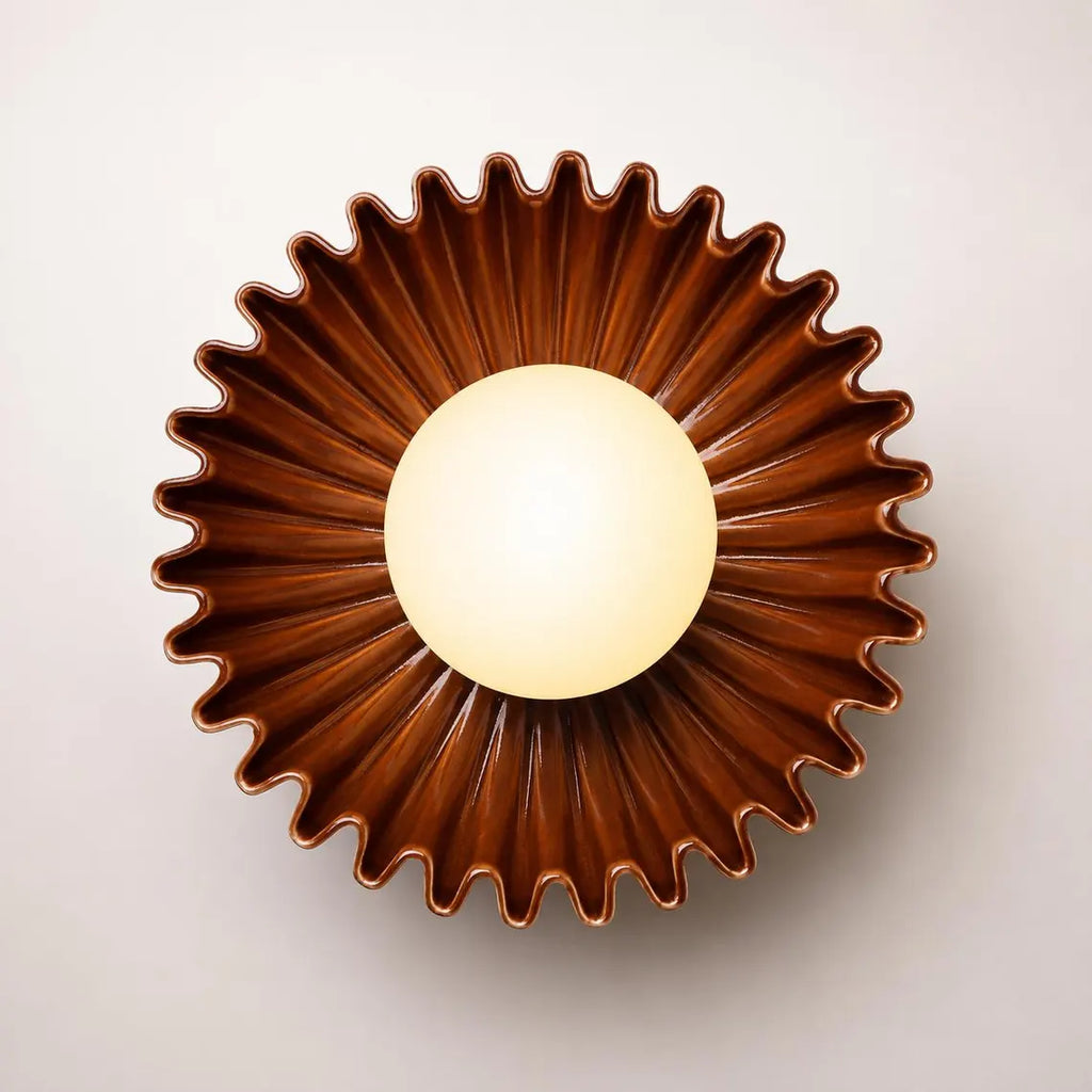 The Solara brown ceramic wall sconce lit with warm glow